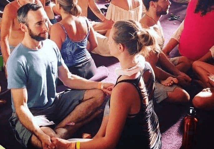 a group of people at a Tantra event sit cross-legged, eye gazing